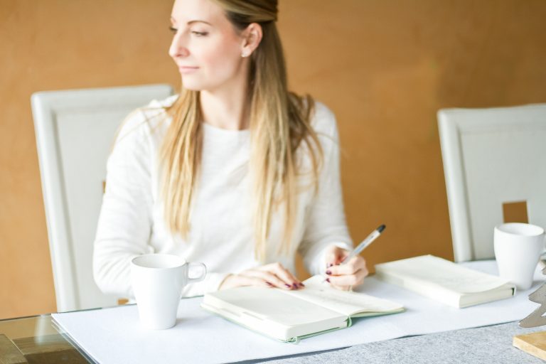 Woman siting at desk and writing in a notebook