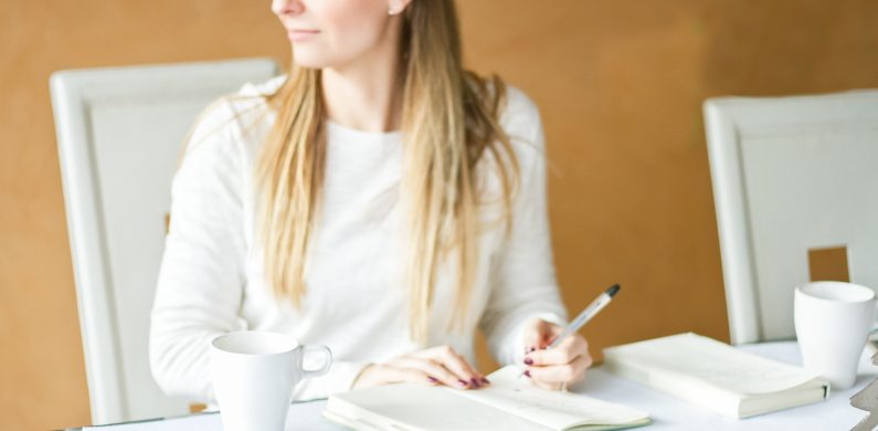 Woman siting at desk and writing in a notebook