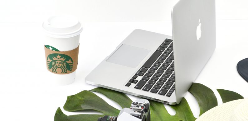 Macbook computer with camera and Starbucks coffee cup