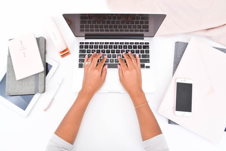 woman typing on a laptop with a phone nearby